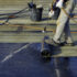 Worker preparing part of bitumen roofing felt roll for melting by gas heater torch flame. On the back of the sheath there is the stamp "Made in Italy" product